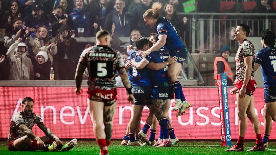 Wakefield players embrace Jayden Myers after his try early in the second half against Leigh
