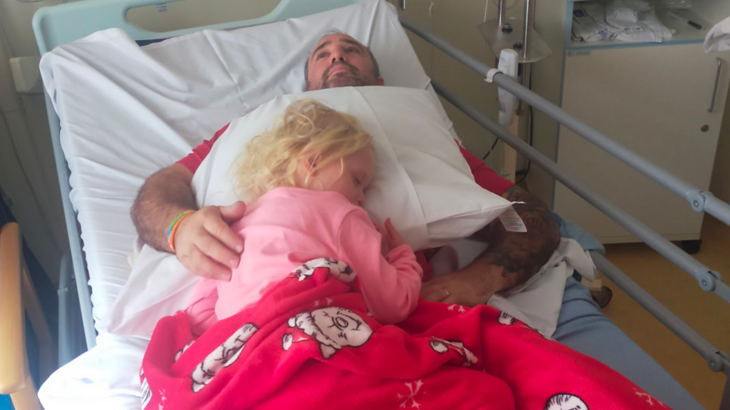 Noa-Rose yn cysgu ar Scott yn yr ysbyty. 