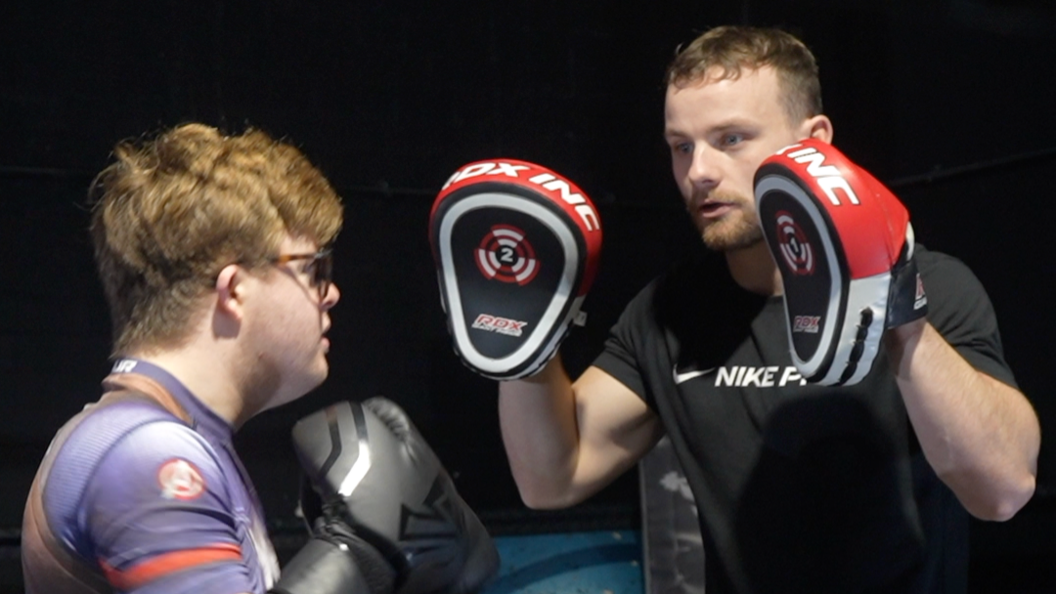 The two men are pictured sparring in a boxing ring. Edward Wagland is wearing boxing gloves while Callum Foster faces his with boxing pads on his hands.