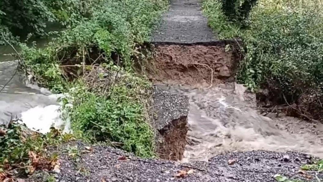 The path, partially collapsed, with water flowing through it.