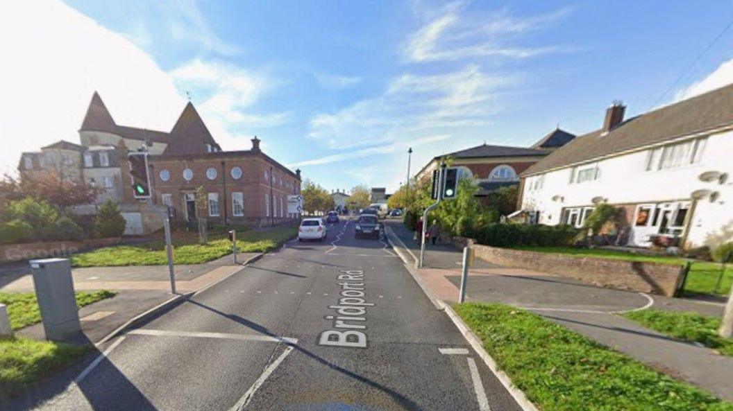 Road with traffic lights and crossing - traffic can be seen in the distance and buildings are on with side.