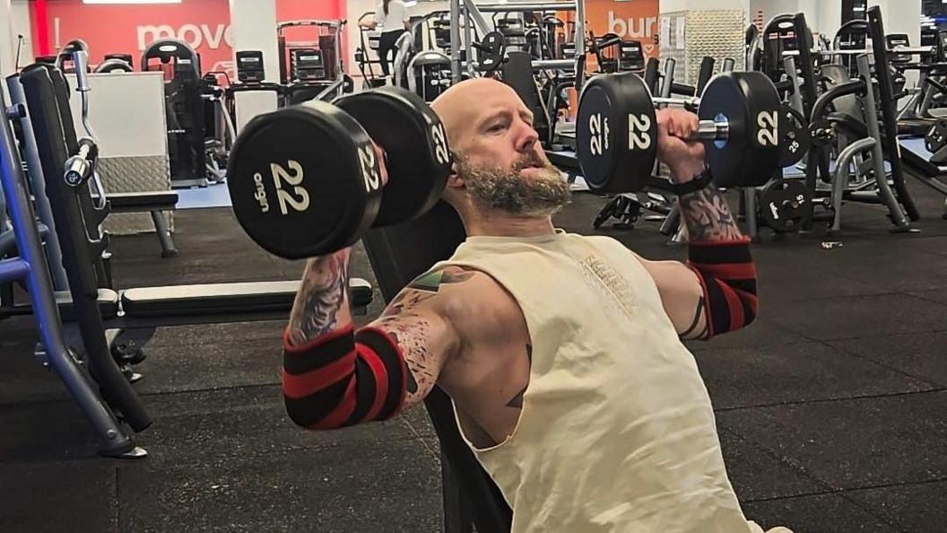 Wayne I'Anson pictured lifting a set of 22kg dumbells in the gym.