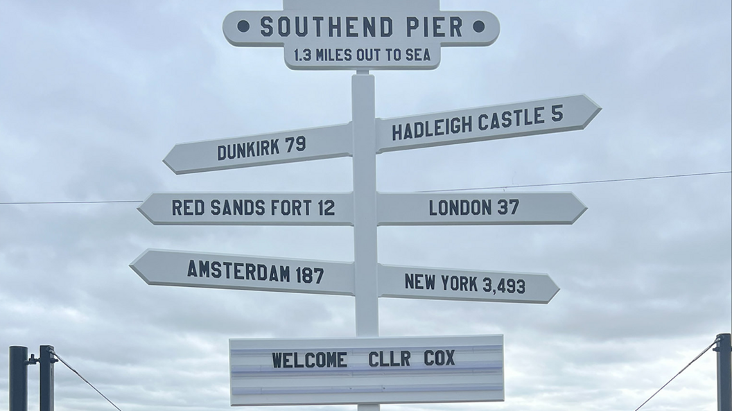 A white signpost with six different branches outlining how fair certain locations are including America and Hadleigh Castle 