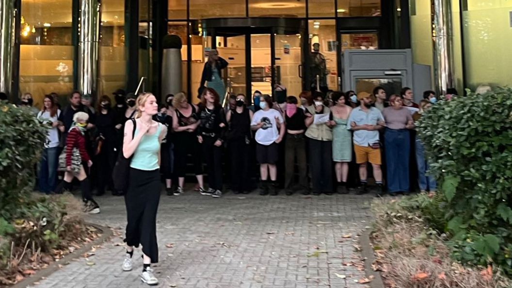 Protestors pictured in a line with arms linked in front of a hotel