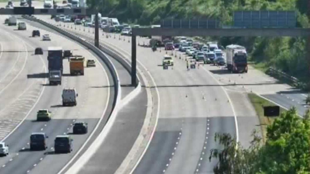 A photo from a traffic camera on the M1 showing police at the scene of a crash and a road closure in place.