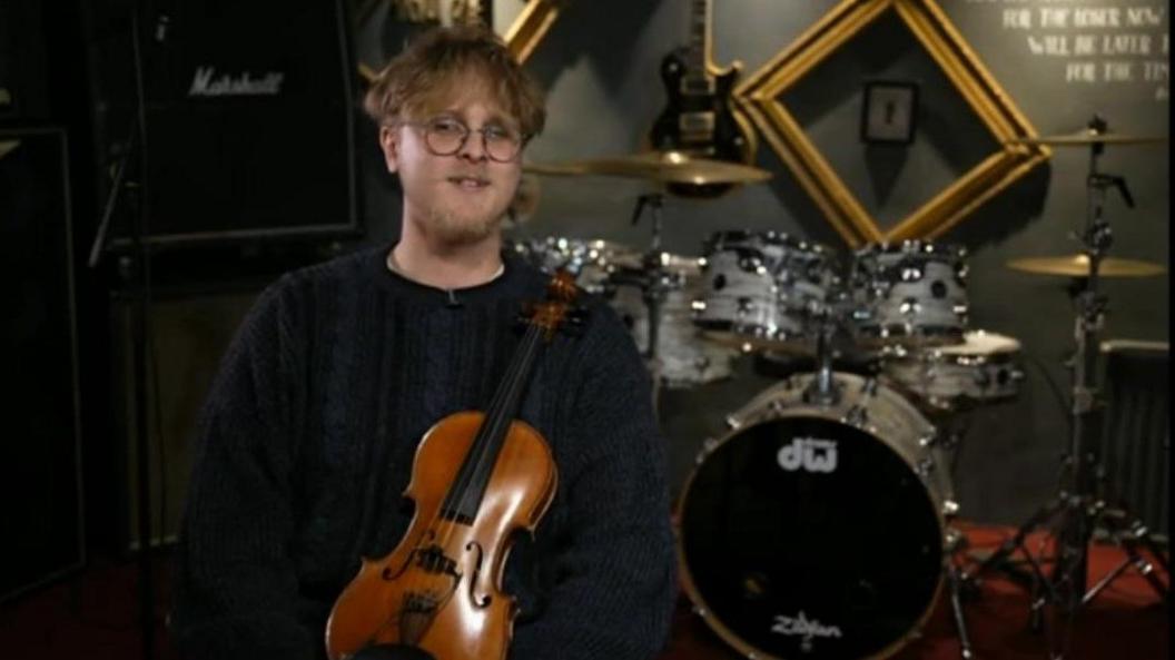 Violinist Theo Warrington holding a violin in a music studio