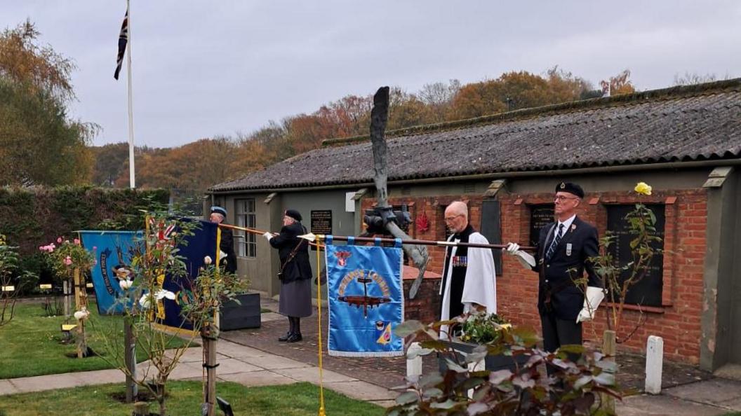 Standard-bearers observe a minute's silence along with a vicar at the memorial service in Elvington.