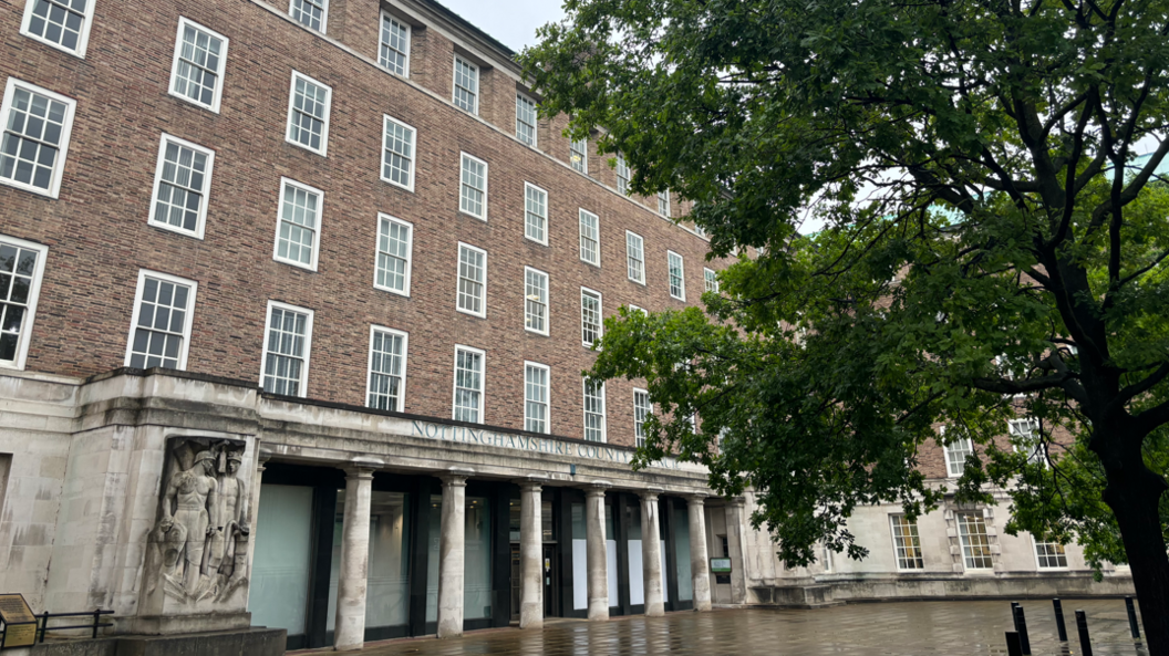 Nottinghamshire County Hall, a red brick building, is pictured, with a tree to the right of the image.