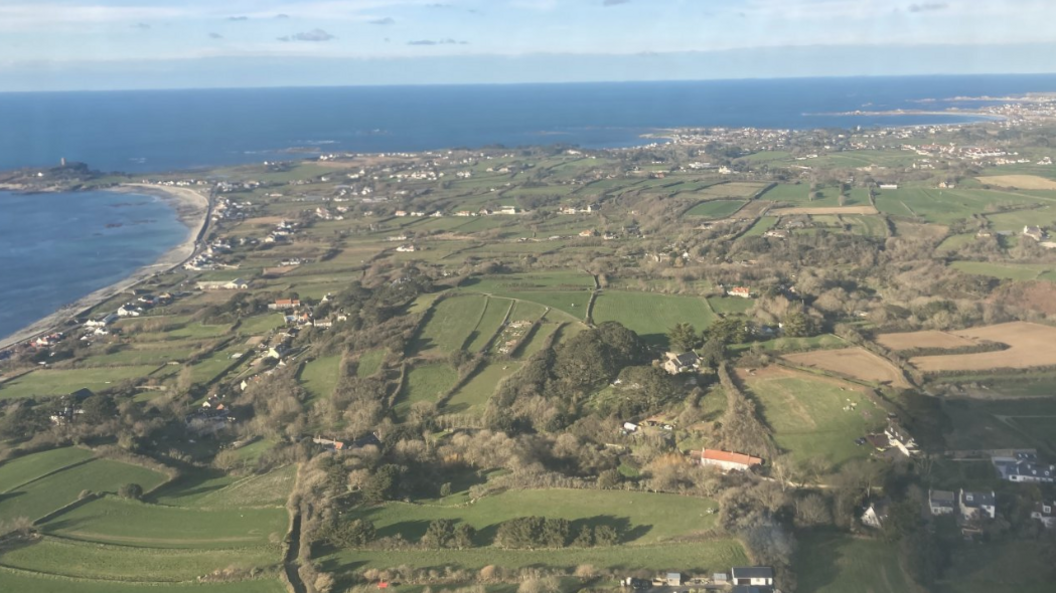 Aerial view of a coastline with fields and houses.