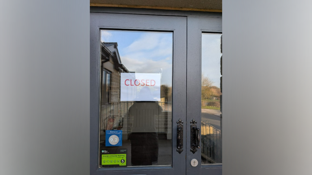 A white sign with red lettering saying 'closed' on a glass door.