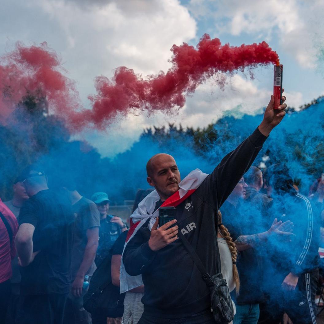 A man holds a flare during a protest outside The Bell Hotel on July 31, 2025 in Epping, England. 