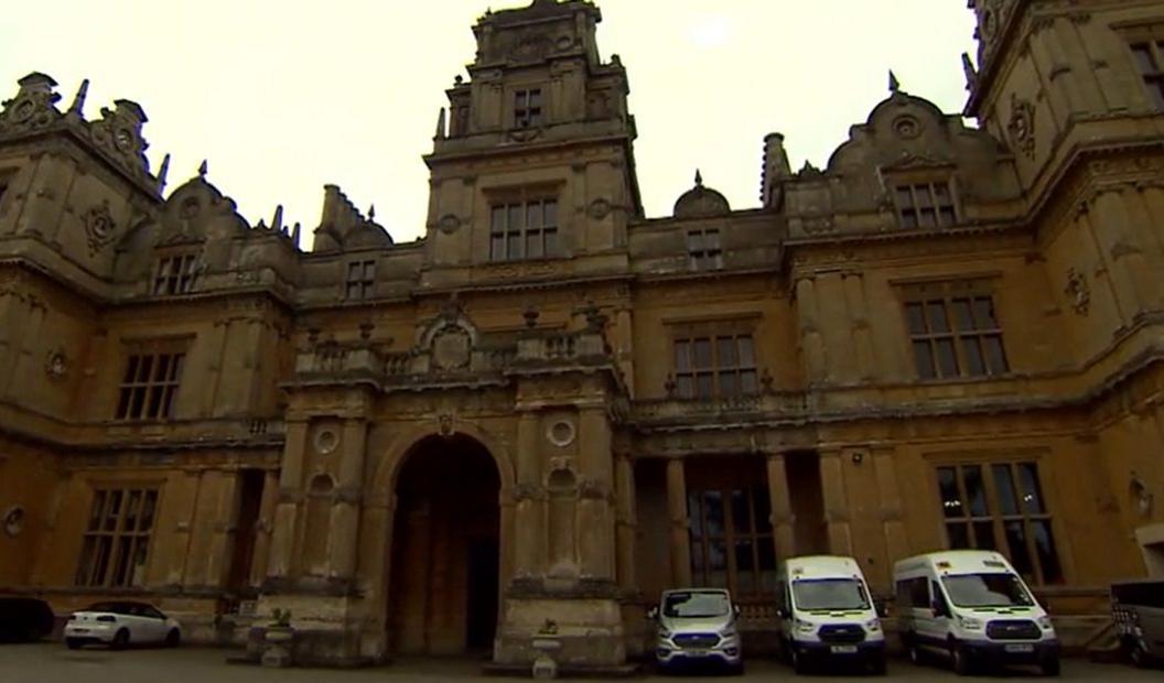 Entrance to school with white vans parked outside.