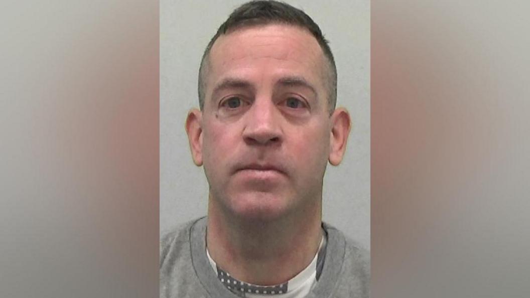 Mugshot of Hodgson. He is clean shaven with a long thin head and short dark hair.