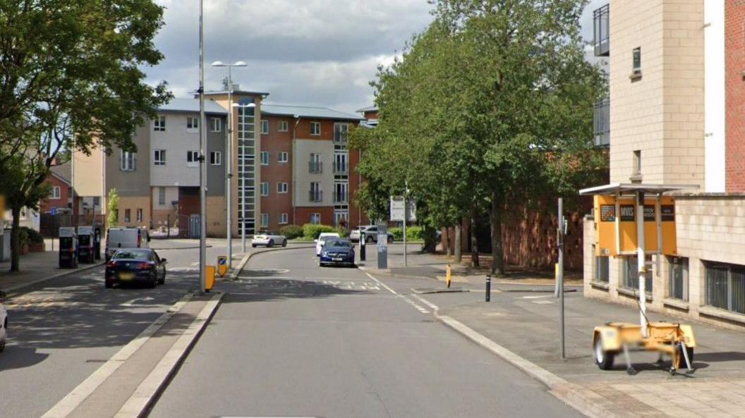 A stretch of city street, curving off to the right in the distance. The road is dual carriageway with a kerb down the middle.