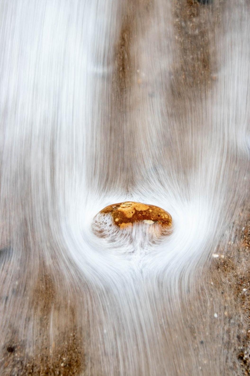 Waves wash past a pebble on the beach