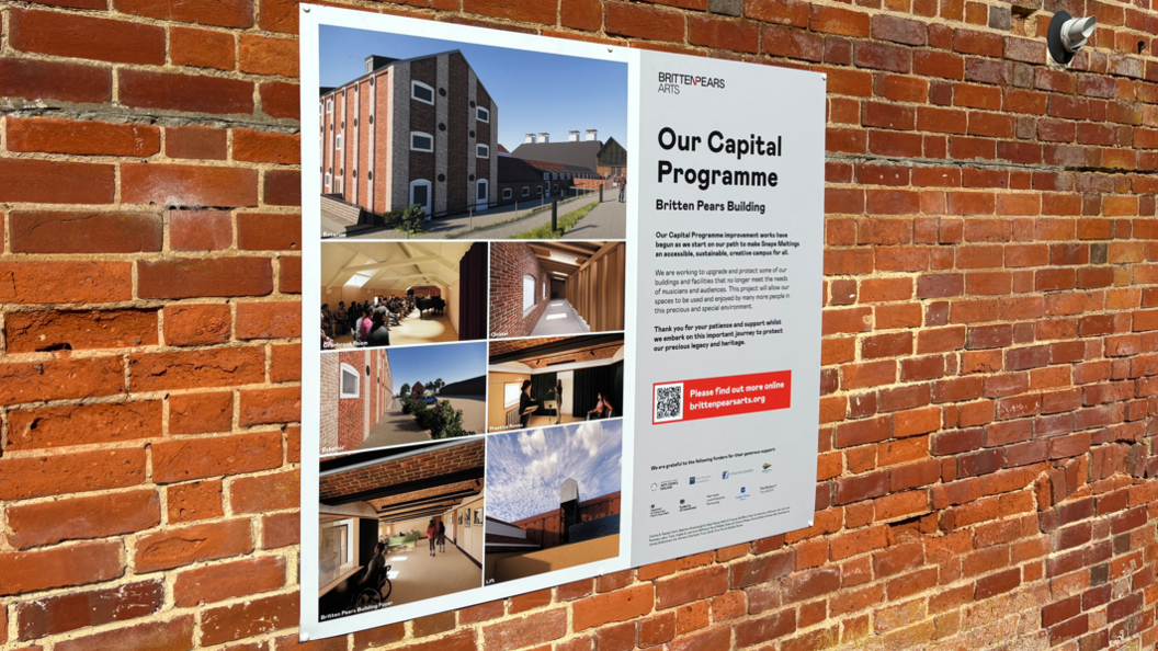 A sign attached to a brick wall. It reads Our Capital Programme - Britten pears Building. It includes images of the building and a description of the work that will be carried out to improve it