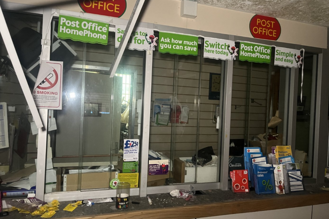 dark post office with desk with leaflets and rubbish on top