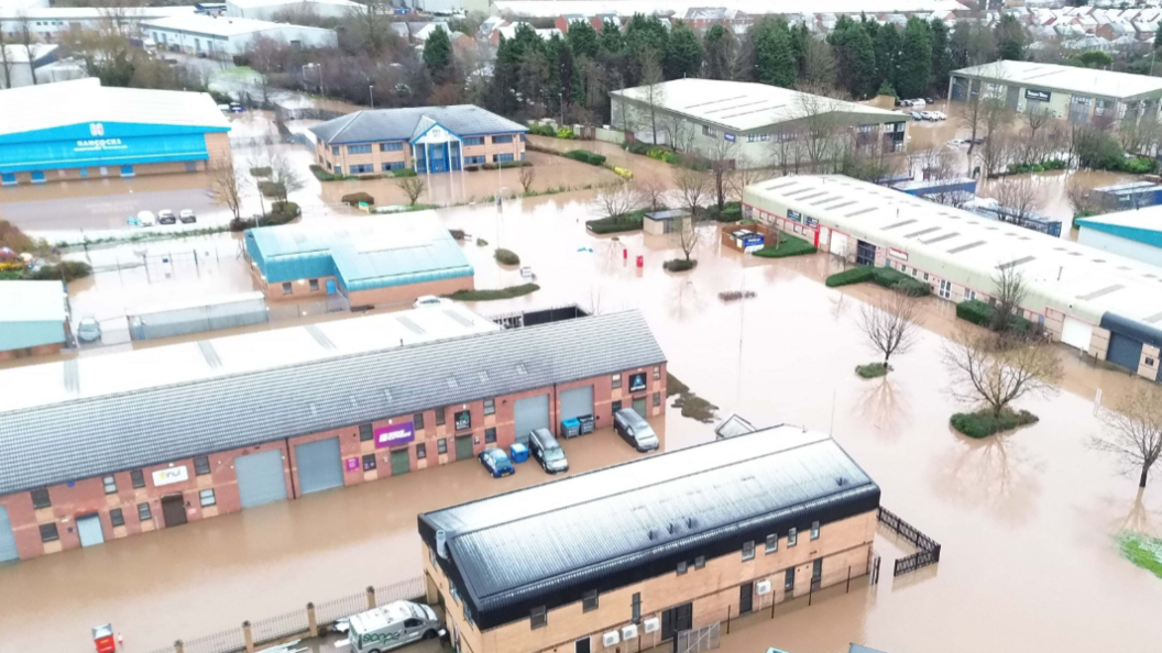 A flooded industrial estate with brown water covering most of the ground.