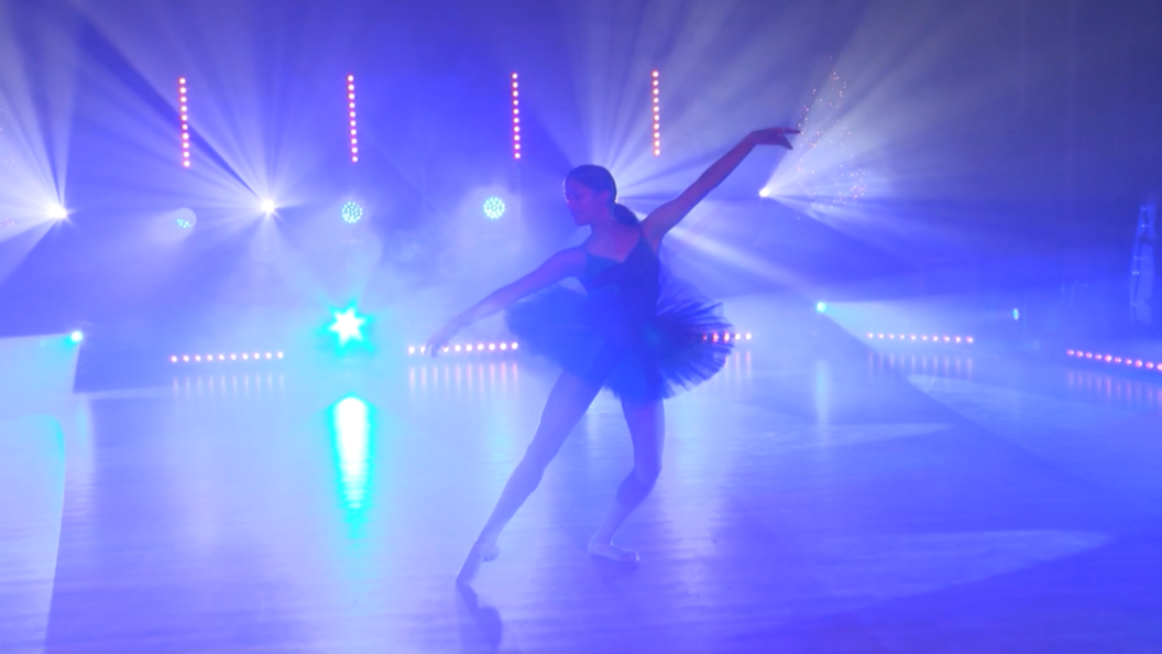 Jemima performing on stage. Behind her is purple lights and she is wearing a tutu. 