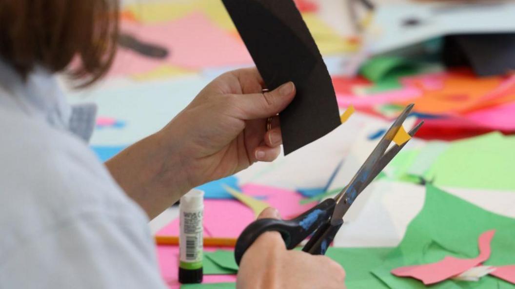 A woman cutting a piece of paper with some scissors