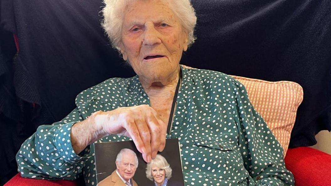 Ethel Caterham proudly holds her card from the King to mark her 115th birthday