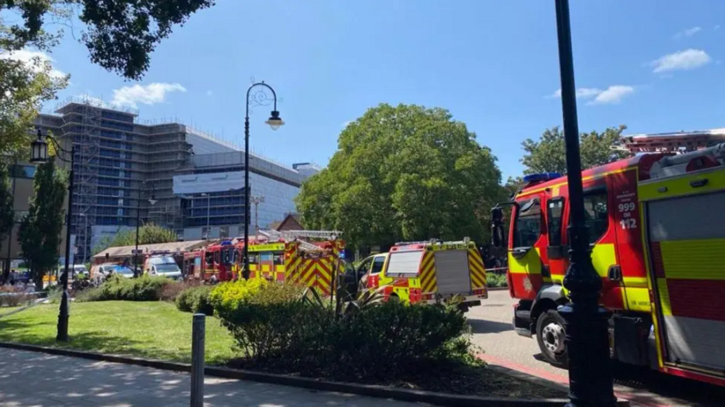 A number of fire trucks and cars parked outside the front of a tower block
