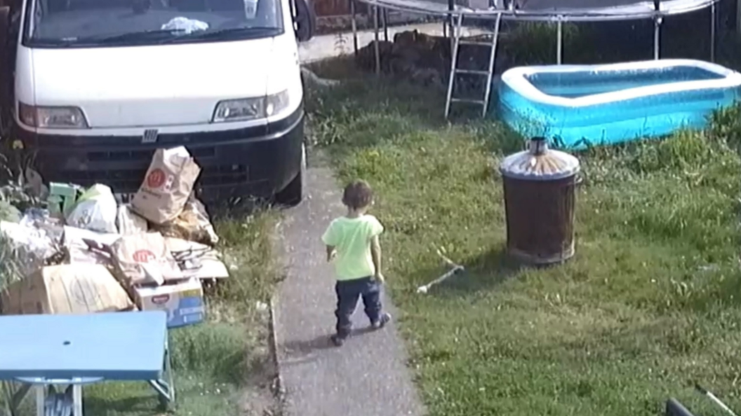 CCTV in the Ives' garden shows Ethan walking down a cement path, he is wearing socks, black trousers and a neon yellow t-shirt. To his left is grass and lots of rubbish, a blue plastic picnic table and a van. To his right is something, perhaps metal, lying in the grass next to a rusting bin. In the grass is a blow up paddling pool and a trampoline.