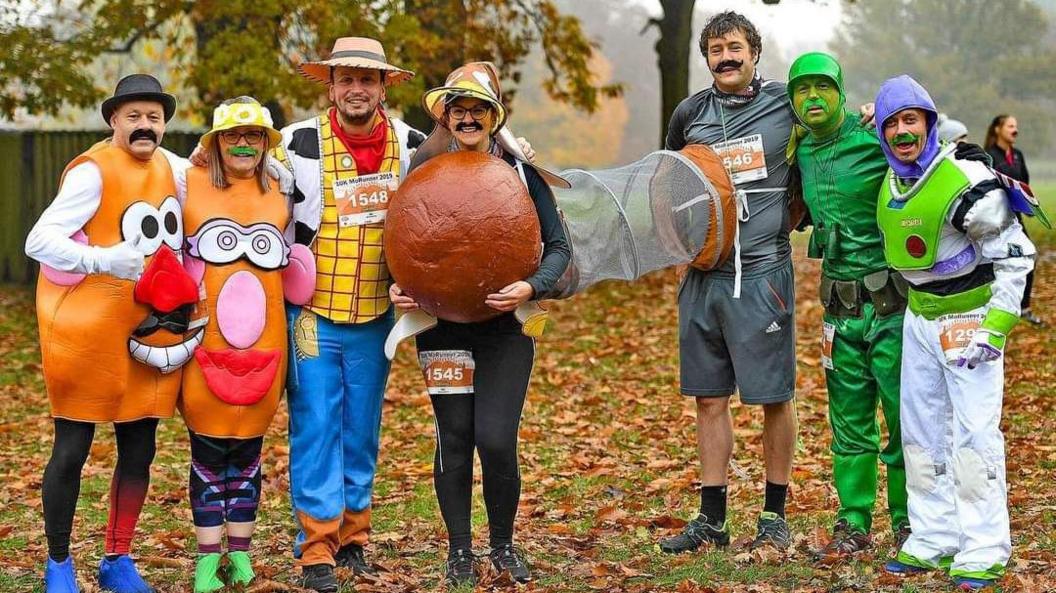 A group of runners dressed as Toy Story characters wearing fake moustaches. They are dressed as Mr and Mrs Potato Head, Woody, Slinky Dog, Sarge and Buzz Lightyear.