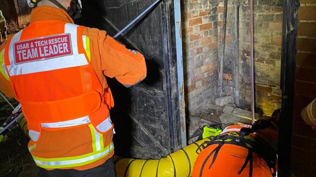 Firefighters trying to pull out a dog from a well