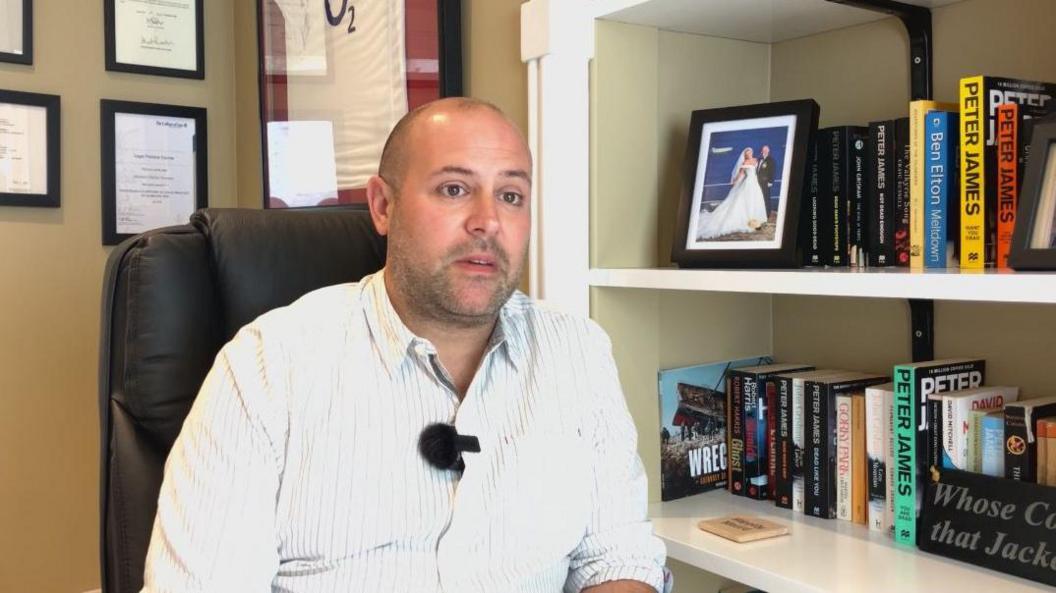 A man with a shirt in front of a book case