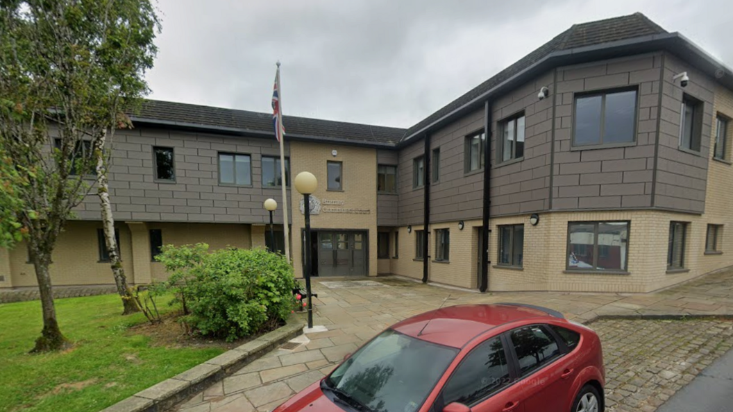 A Google Streetview of the exterior of Burnley Crown Court. It is a combination of grey panels and cream bricks. There is a flag pole with the union flag hanging from it.