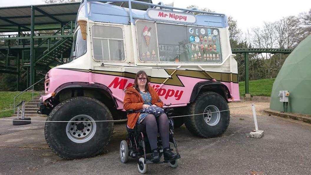 A woman in a wheelchair next to an monster truck ice cream van