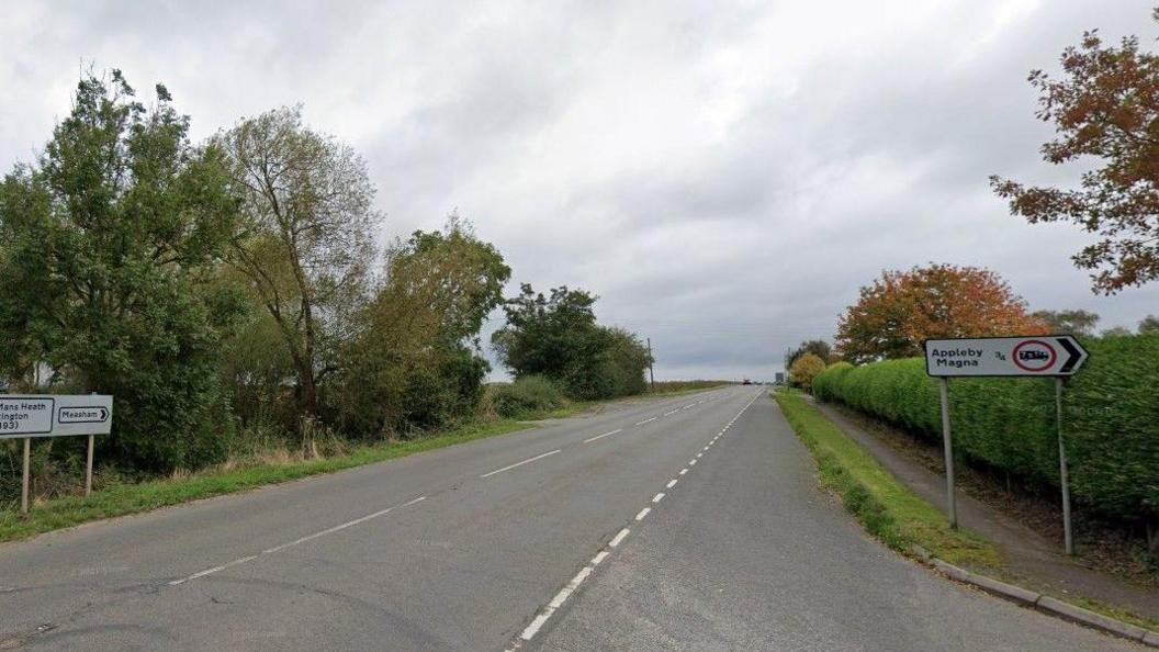 Tamworth Road in Leicestershire, showing a sign on the right of the road for Abbleby Magna and a sign on the left for Measham. The road is tree-lined.