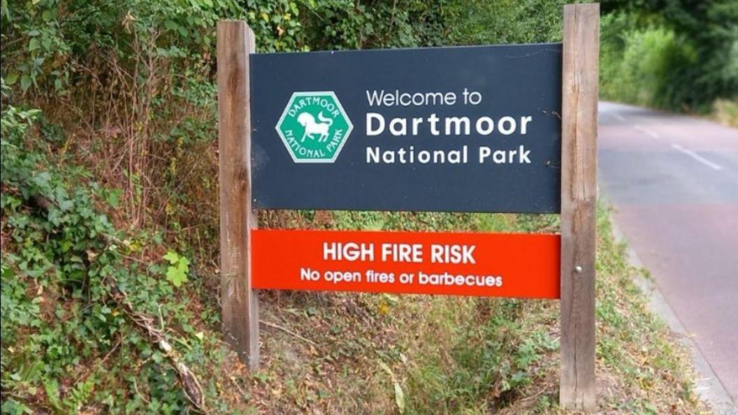 A sign that says Welcome to Dartmoor National Park - High Fire Risk - no open fires or barbecues.