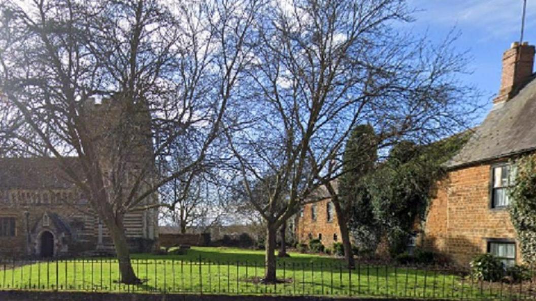 Grey stone church and brick pub building separated by grass