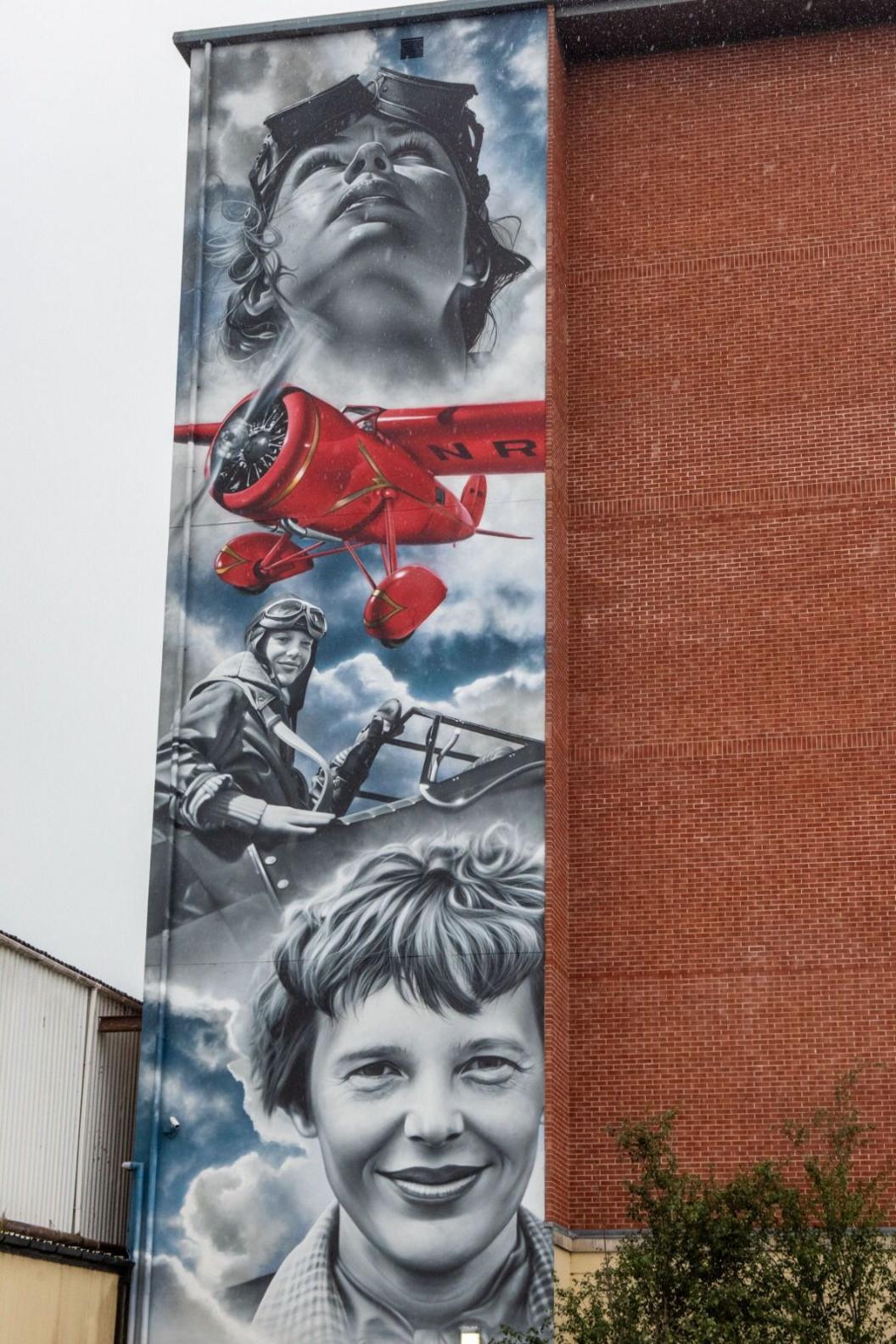 A mural celebrating Amelia Earhart spanning the full length of a building in Derry. She is pictured along with her red lockheed plane