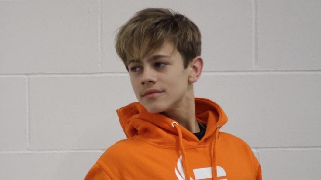 Samuel in an orange hooded sweatshirt