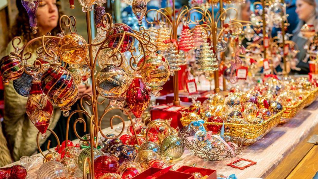 A stall counter containing various colourful Christmas decorations, including baubles to hang on Christmas trees. 