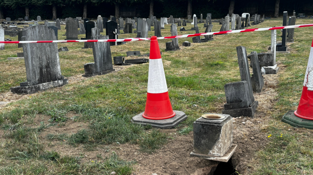 A cone and tape around a grave damaged by badgers