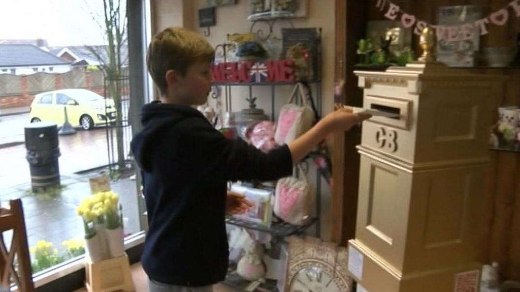 Boy posting letter into gold postbox