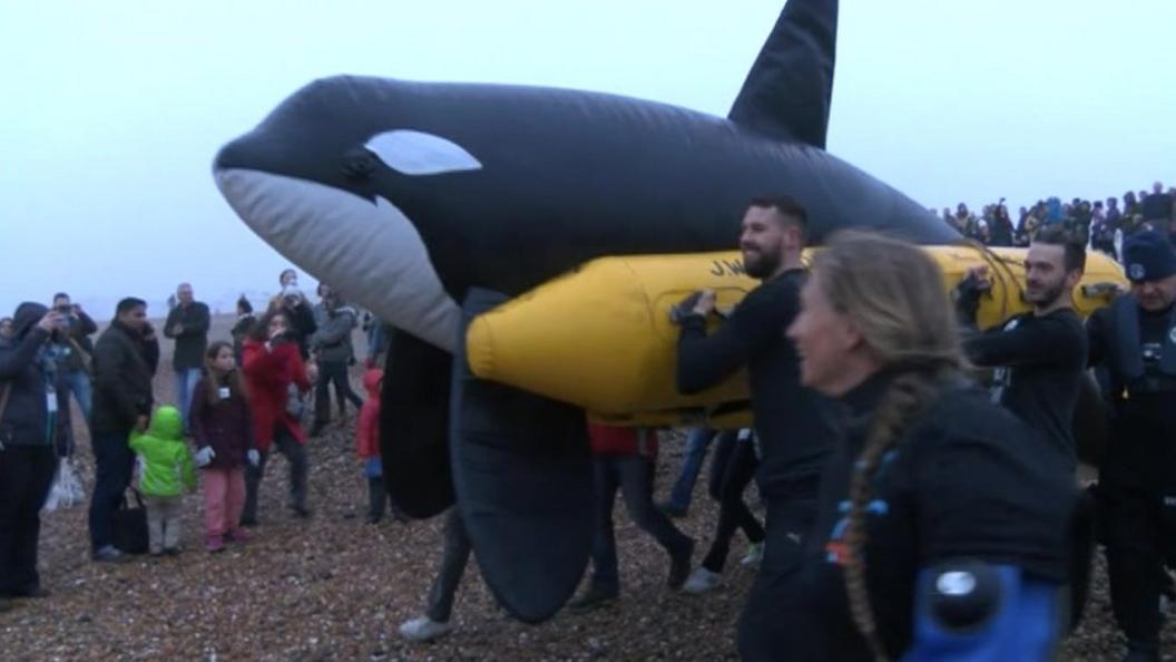 People carrying killer whale model