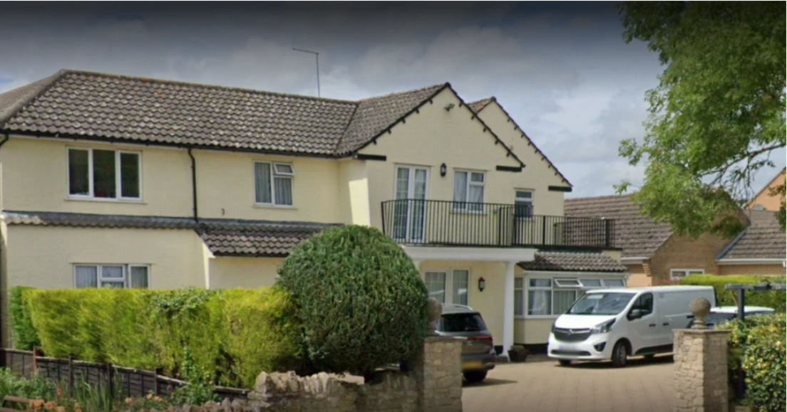 A two storey yellow building with a black iron balcony on the front of the property. A white van is parked outside.