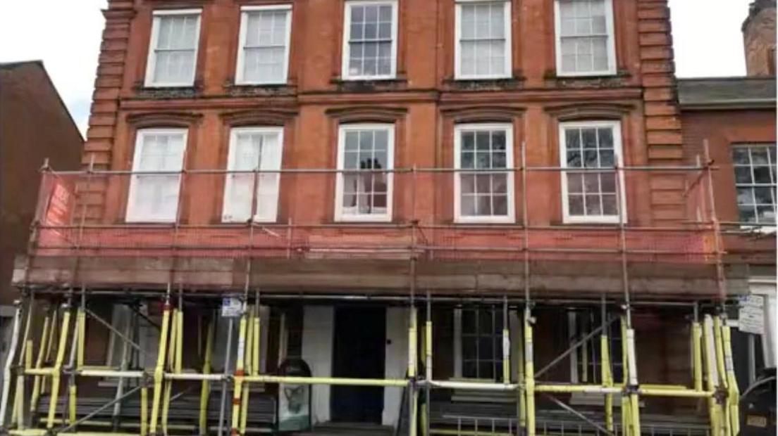 The exterior of Wilmer House, and red brick three-story building, with scaffolding around it.