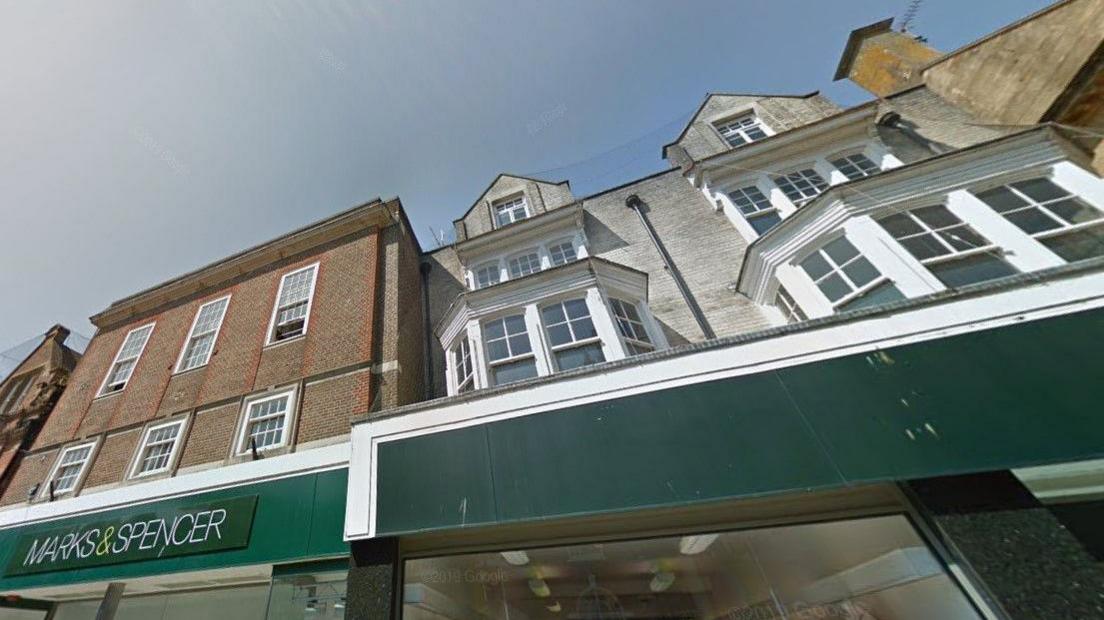 View from the street of the brick-built upper floors of the M&S buildings with white framed sash windows and bay windows