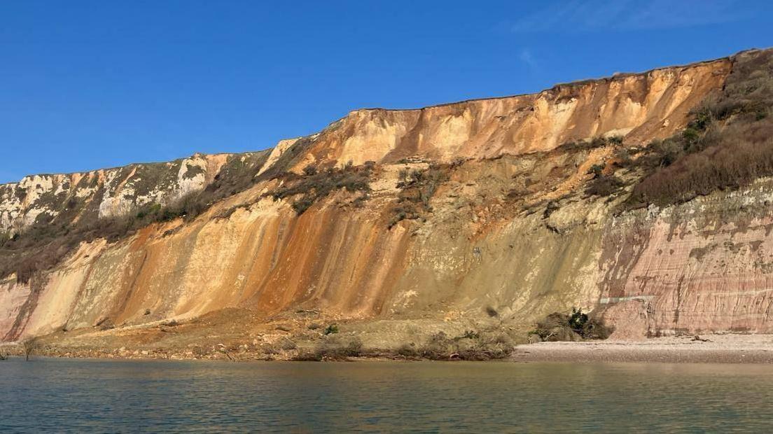 The cliff fall seen in the distance with the photo taken from a boat at sea. 