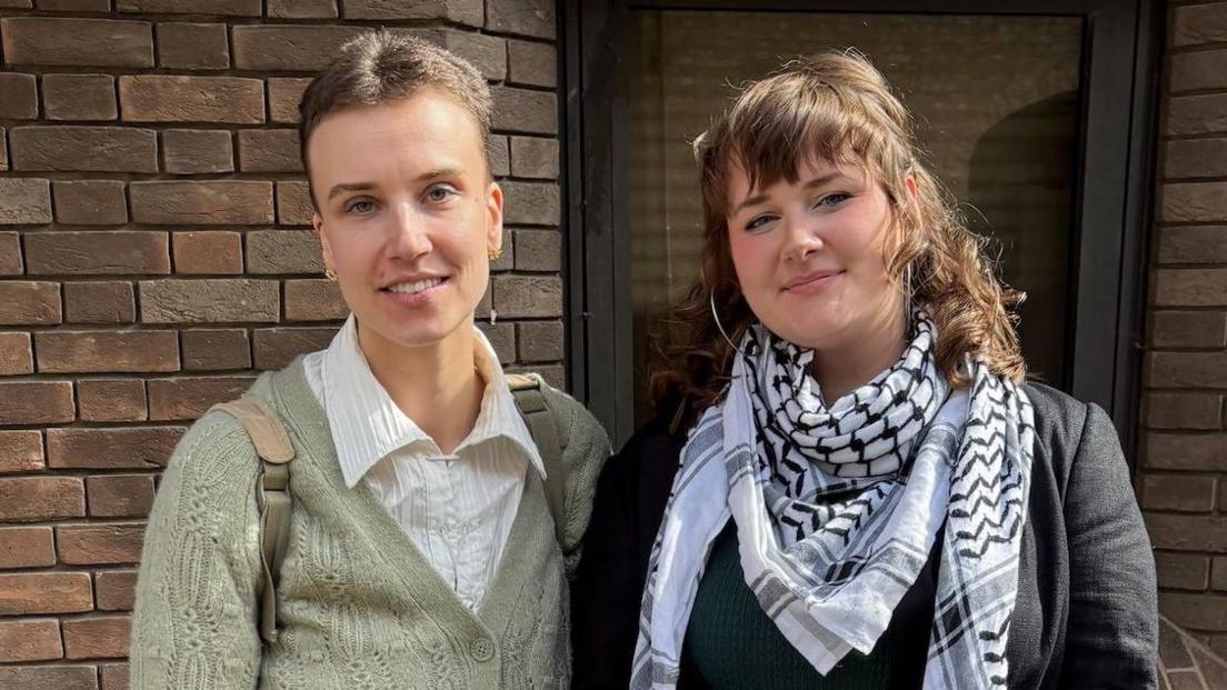 Jennifer Kowalski, 29, (left) looking directly at the camera and smiling. Next to her is Cole MacDonald, 23, who is also looking directly at the camera and smiling. The pair are both standing outside in front of a brick wall.