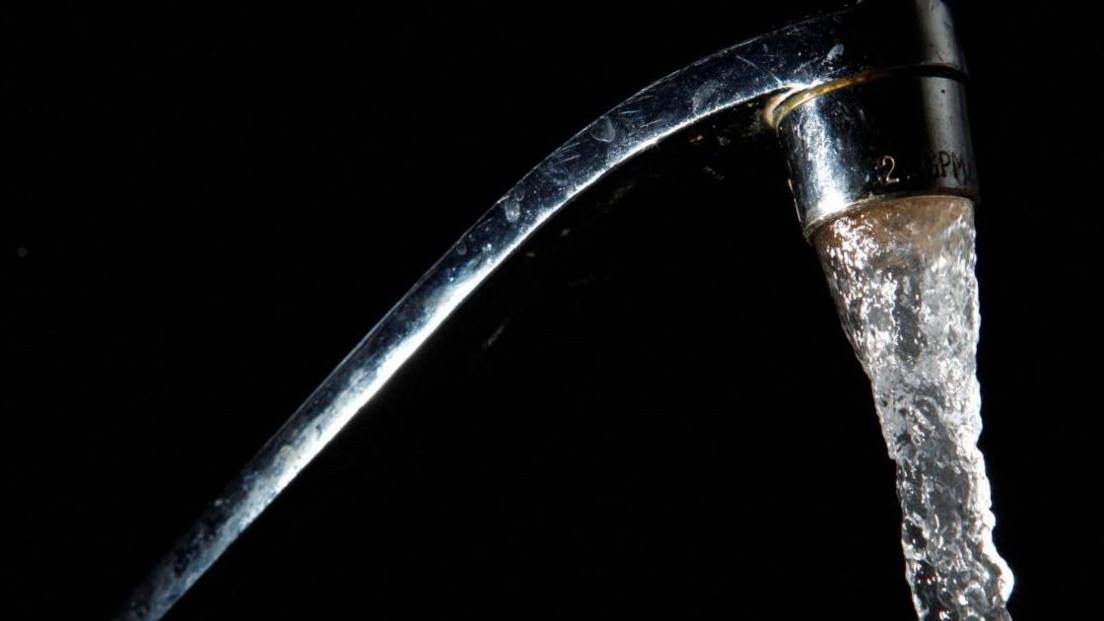 Water flows out of a chrome tap