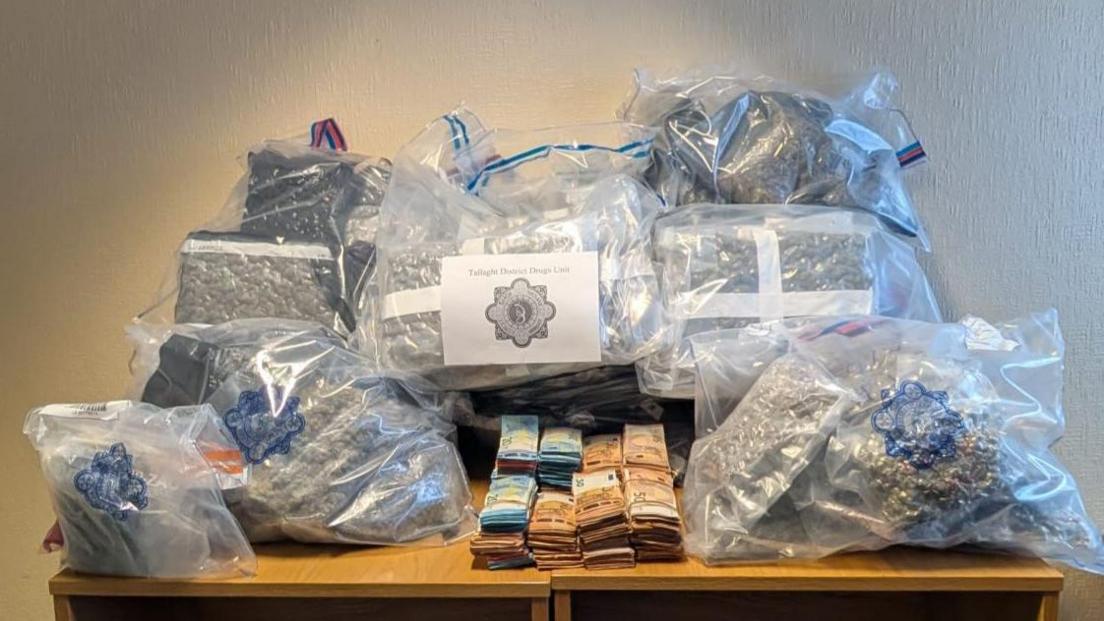 A wooden table with bags of drugs sitting on top of it and cash in euros.