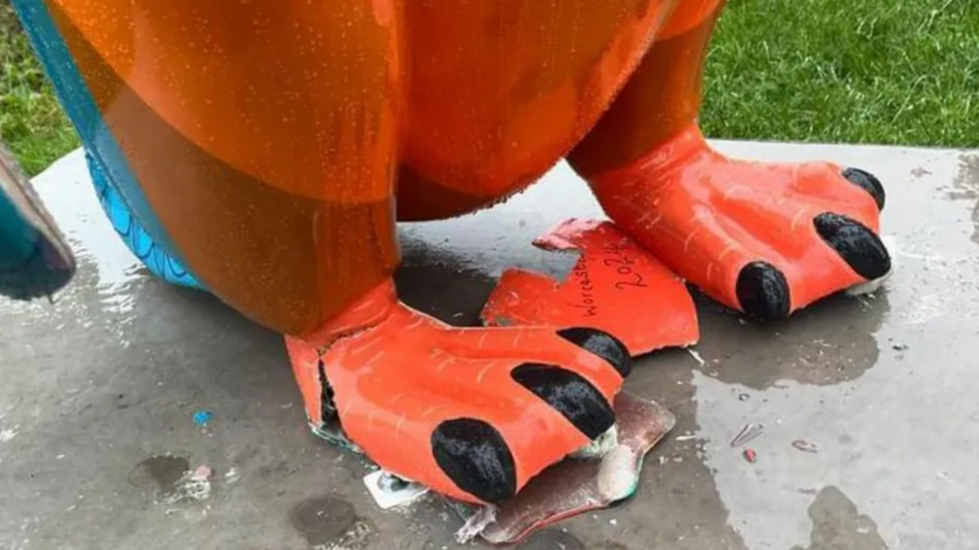 Blue and orange penguin sculpture with a cracked and damaged foot