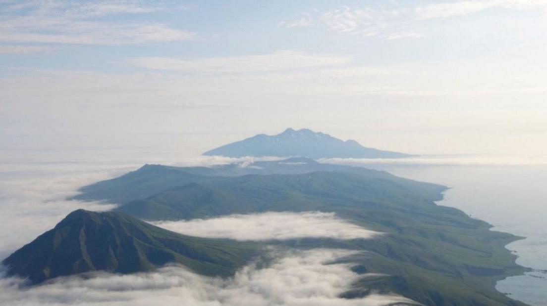 A group of islands seen from above with clouds over them